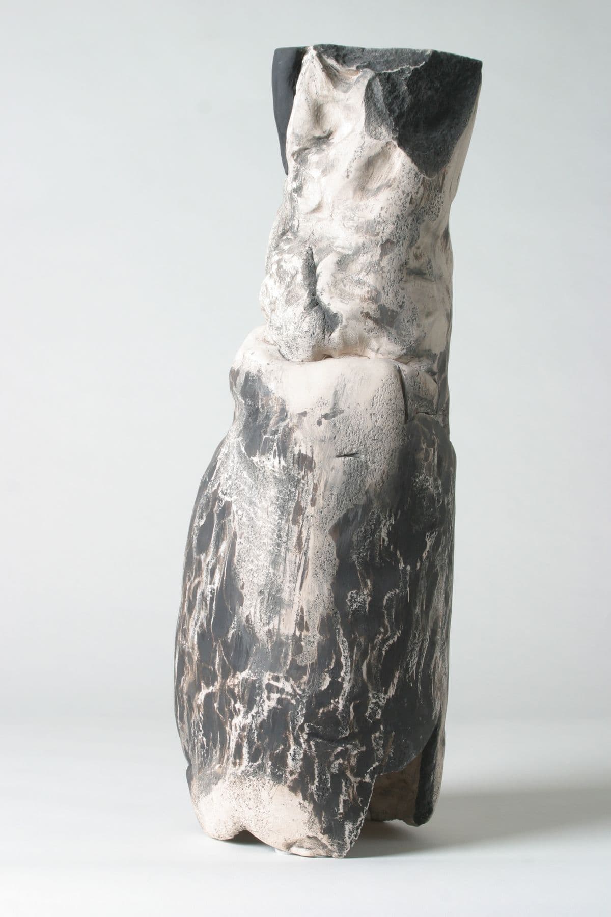 Abstrakte Keramikskulptur eines sitzenden Torsos . Die Glasur wechselt von Grau zu Weiß im oberen Bereich.